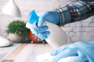 Hand Blue Rubber Gloves Holding Spray Bottle Cleaning Table
