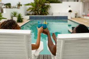 Couple Toasting Glasses Cocktail While Relaxing Sun Lounger Near Swimming Pool