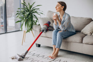 Woman With Accumulator Vacuum Cleaner Drinking Coffee