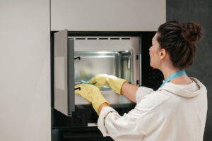 Woman Yellow Gloves Cleaning Oven 1