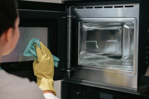 Woman Yellow Gloves Cleaning Oven