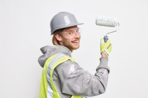 Man Paints New Home Holds Roller Wears Protective Helmet Glasses Uniform Does Repair Poses White