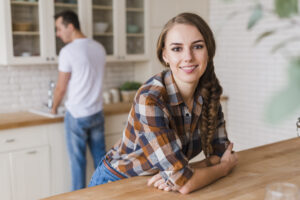 Smiling Woman Leaning Table While Man Washing Dishes