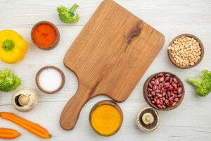 Top View Chopping Board Mushrooms Broccoli Beans Bowls Different Spices Cut Carrots Yellow Bell Pepper Table