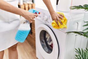 Young Hispanic Woman Cleaning Washing Machine Laundry Room