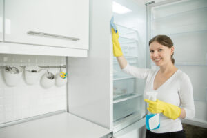 Young Smiling Woman Wearing Rubber Gloves Cleaning Fridge