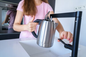 Female Pours Fresh Clean Filtered Purified Water From Tap Into Electric Kettle Boiling Water Kitchen Home