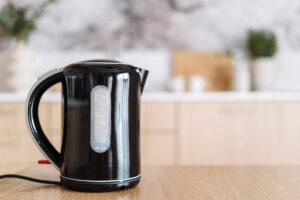 Modern Black Electric Teapot Against Blurred Kitchen Background