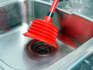 stainless kitchen sink red plunger household work concept