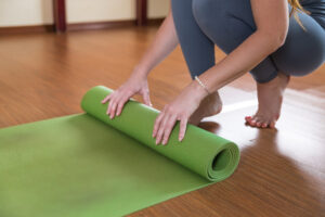 Unrecognizable Woman Roll Up Green Mat Workout Slim Girl Sportswear Finish Doing Yoga Fitness