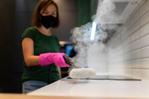 Woman Cleaning Kitchen Furniture With Steam Cleaner