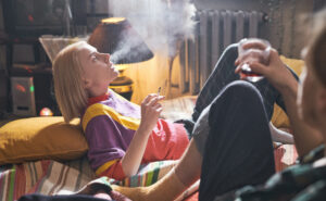 Young Woman Lying Bed Smoking Cigarette With Her Boyfriend Sitting Bed Drinking Wine