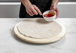 High Angle Man Spreading Tomato Sauce Pizza Dough