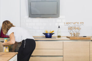 Woman Bending Down Putting Food Cabinet