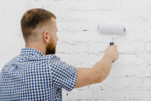 Back View Man Painting Wall With Roller